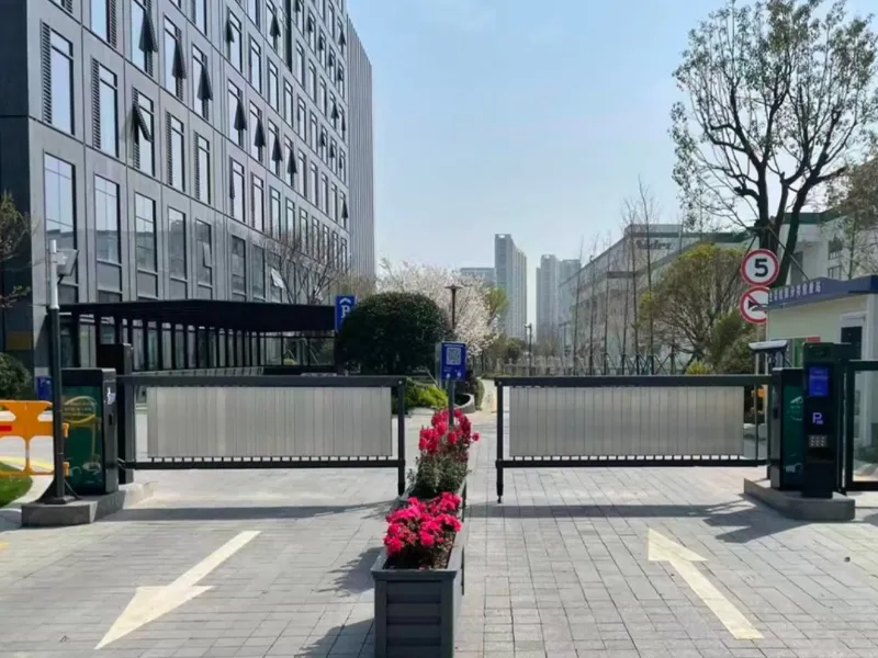 Smart parking entrance with sliding gate and access control terminals at a modern building
